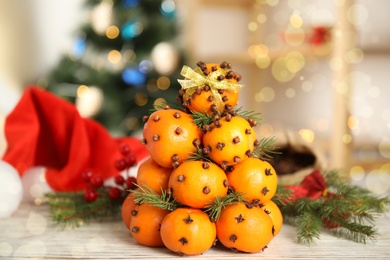 Photo of Pomander balls made of tangerines with cloves and fir branches on white wooden table