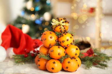 Pomander balls made of tangerines with cloves and fir branches on white wooden table