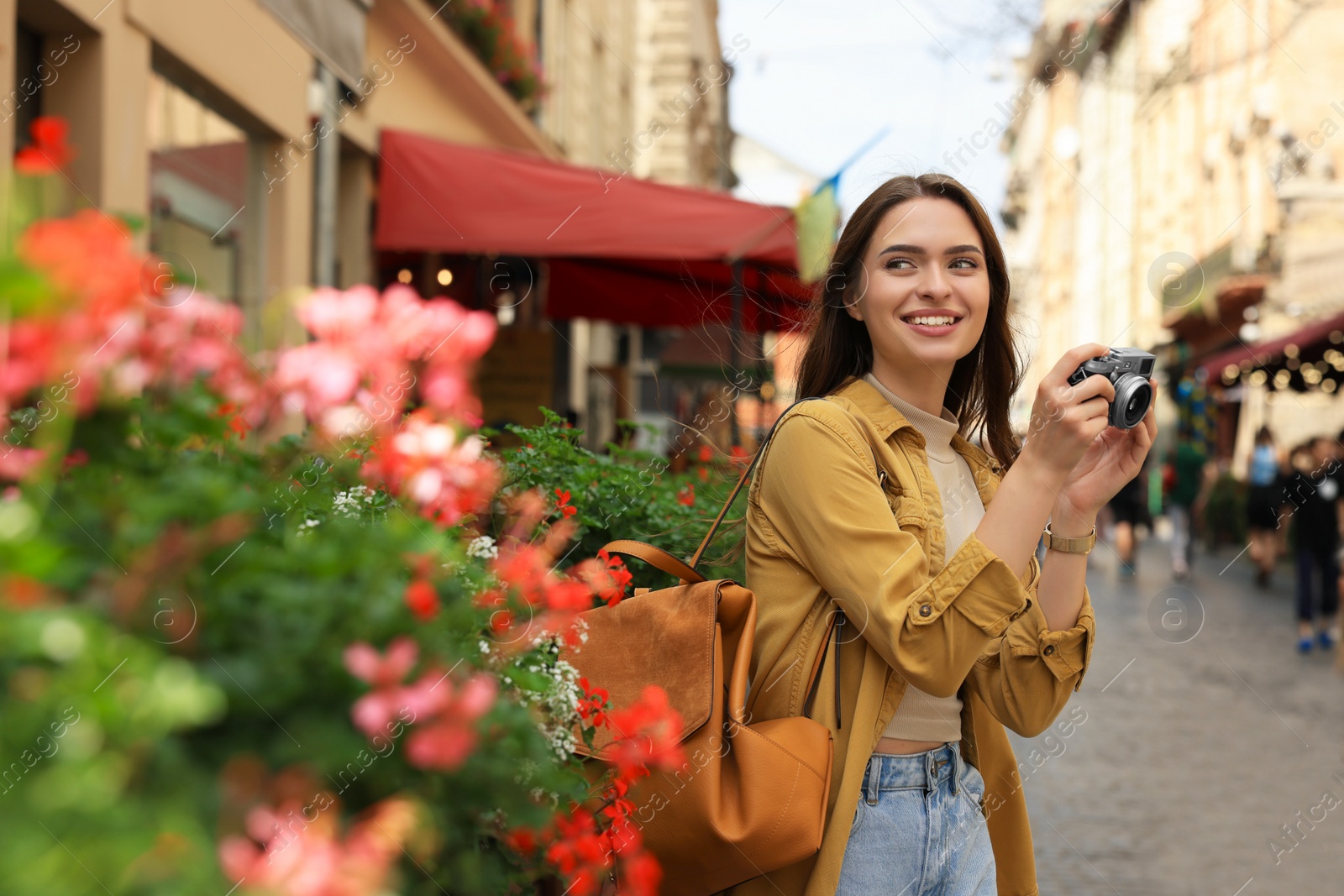 Photo of Young woman with camera on city street. Interesting hobby