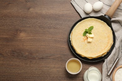 Delicious crepes and ingredients on wooden table, flat lay. Space for text