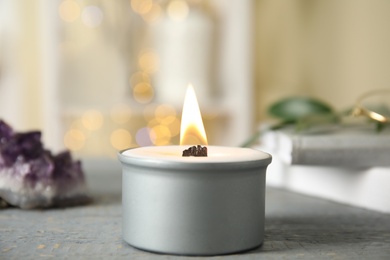 Burning candle with wooden wick on grey table