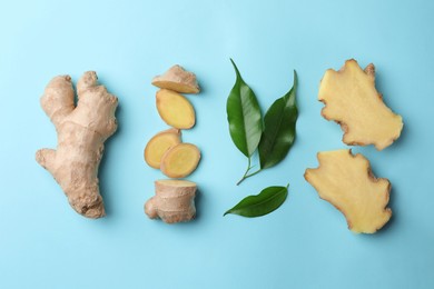 Photo of Fresh ginger with green leaves on pale light blue background, flat lay