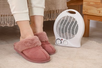 Photo of Woman near modern electric fan heater indoors, closeup