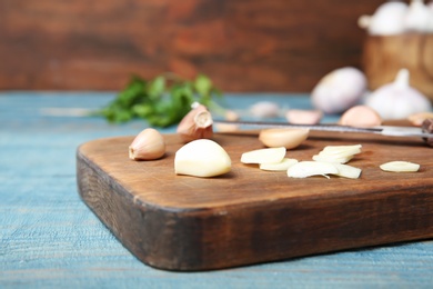 Photo of Wooden board with fresh garlic on table