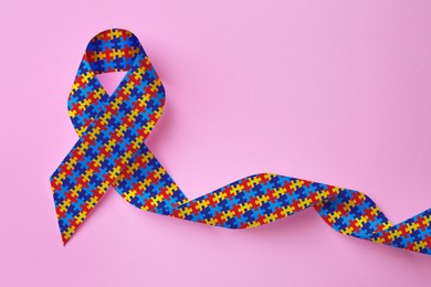 Image of World Autism Awareness Day. Colorful puzzle ribbon on pink background, top view