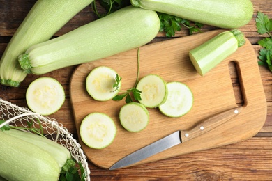 Photo of Ripe green zucchinis and parsley on wooden table, flat lay
