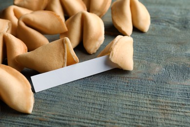 Photo of Tasty fortune cookies and paper with prediction on blue wooden table, closeup. Space for text