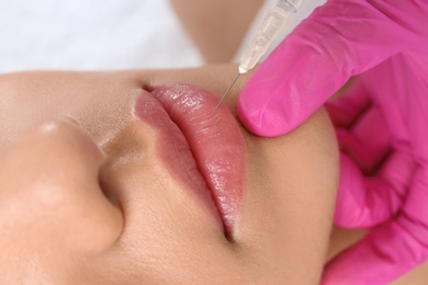 Photo of Young woman getting lip injection in beautician salon, closeup