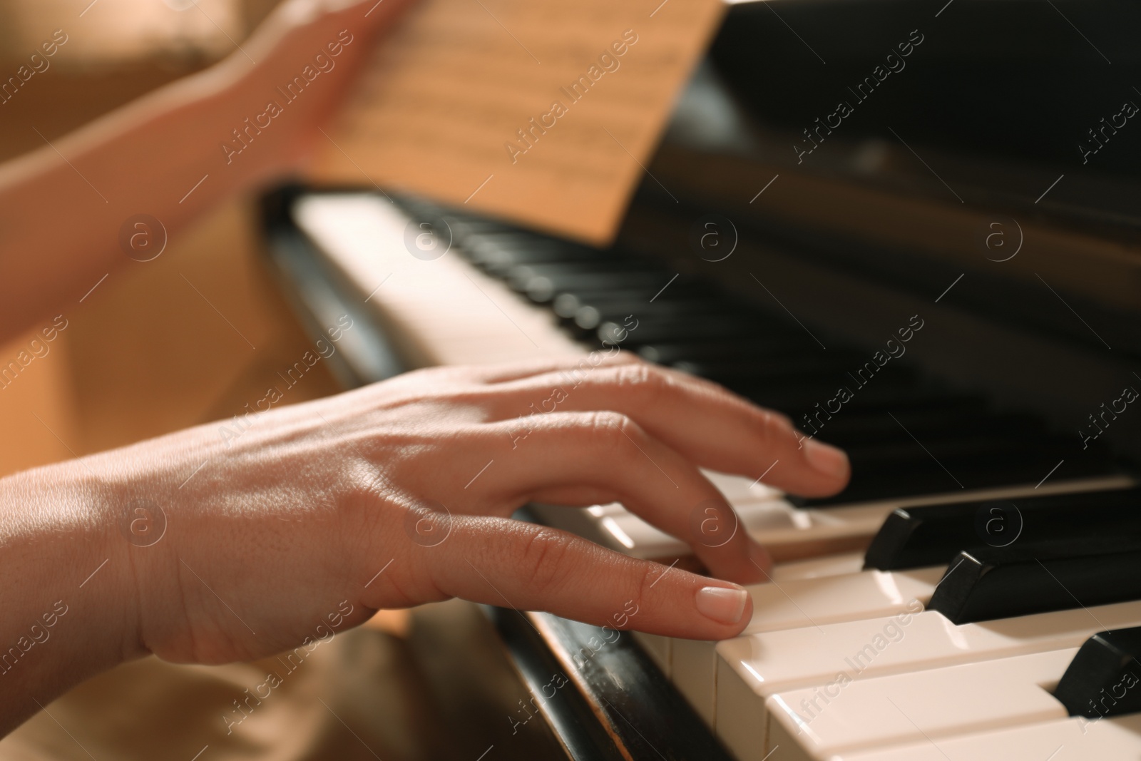 Photo of Young woman playing piano, closeup. Music lesson