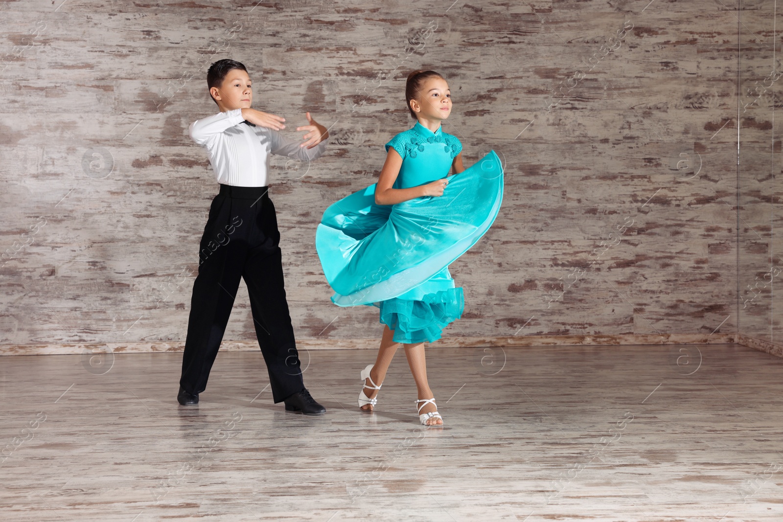 Photo of Beautifully dressed couple of kids dancing together in studio