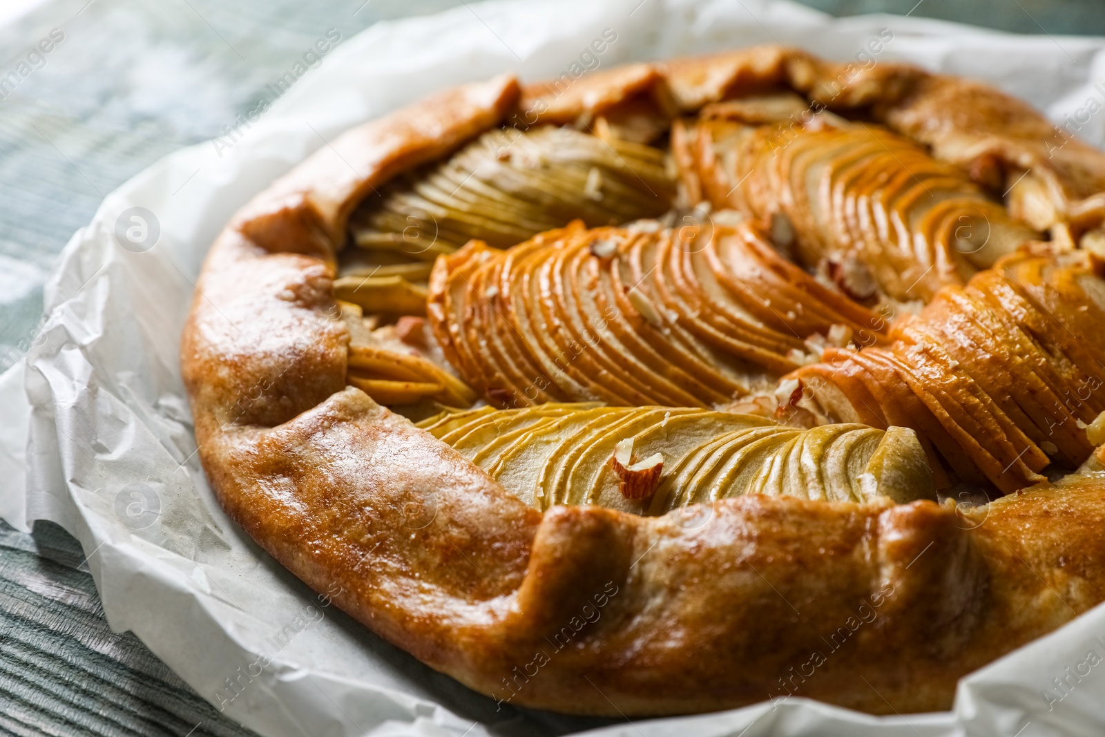Photo of Delicious apple galette with walnuts on wooden table, closeup