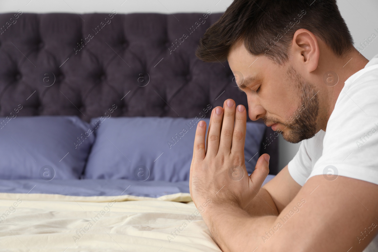 Photo of Handsome man saying bedtime prayer at home. Space for text