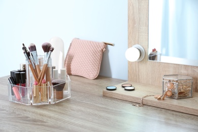 Photo of Organizer with cosmetic products for makeup on table near mirror