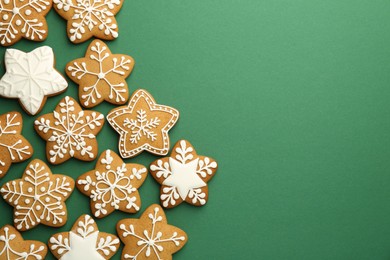 Tasty Christmas cookies with icing on green background, flat lay. Space for text