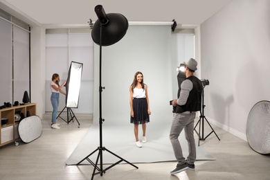 Photo of Professional photographer and assistant working with model in modern studio