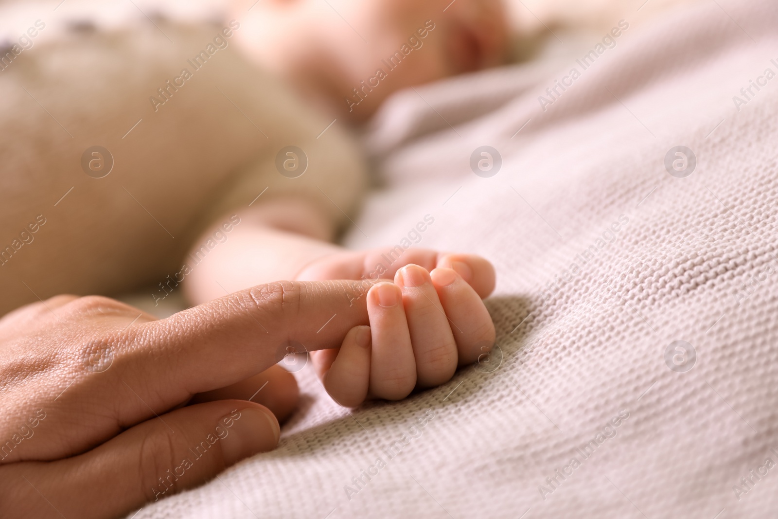 Photo of Mother and her newborn baby on light grey knitted plaid, closeup. Space for text