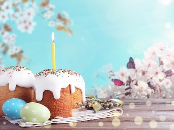 Image of Easter cakes and painted eggs on wooden table outdoors. Space for text