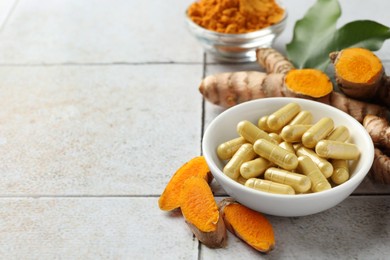 Photo of Turmeric roots and pills on light tiled table. Space for text