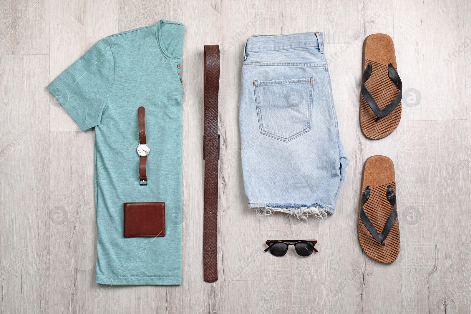 Photo of Set of stylish clothes and accessories on wooden floor, flat lay