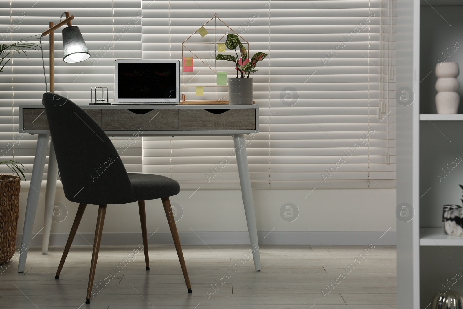 Photo of Cozy workspace with laptop, desk and comfortable chair at home. Stylish interior design