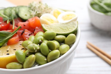 Photo of Delicious poke bowl with quail eggs, fish and edamame beans, closeup. Space for text