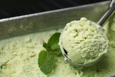 Photo of Container and scoop of sweet pistachio ice cream, closeup