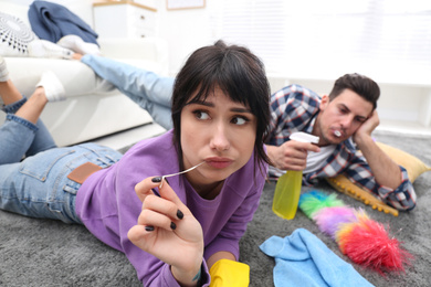 Photo of Lazy couple procrastinating while cleaning at home