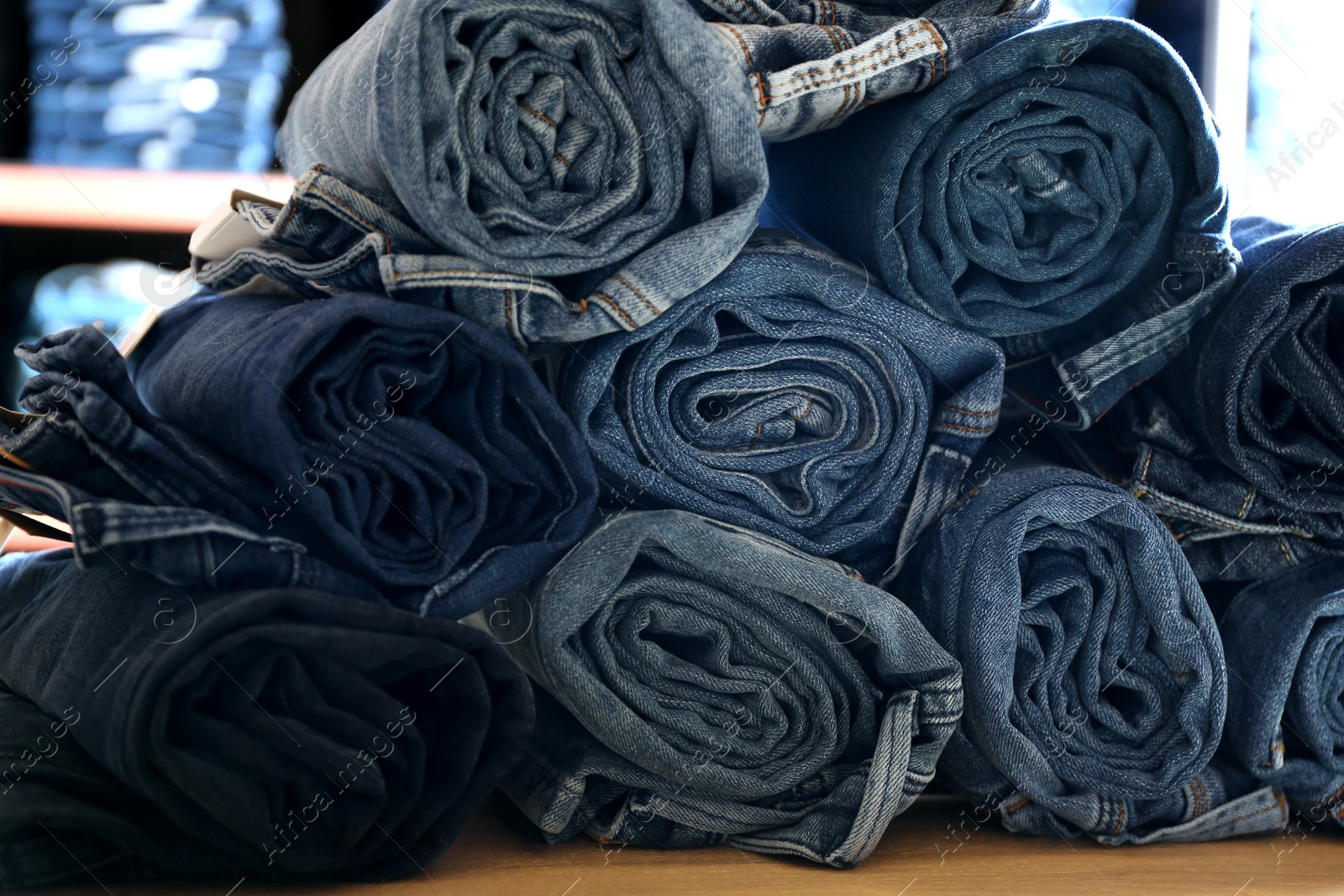 Photo of Rolled modern jeans on display in shop, closeup