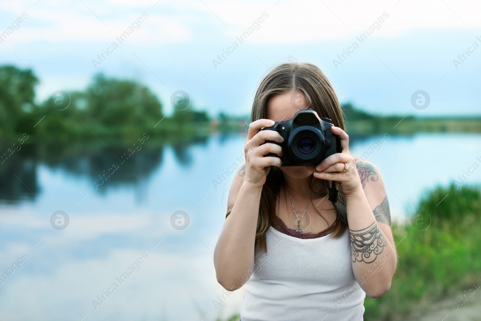 Photo of Young woman taking picture with professional camera outdoors