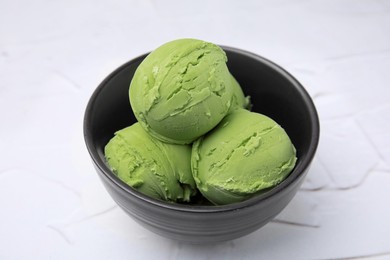 Photo of Tasty matcha ice cream in bowl on white textured table