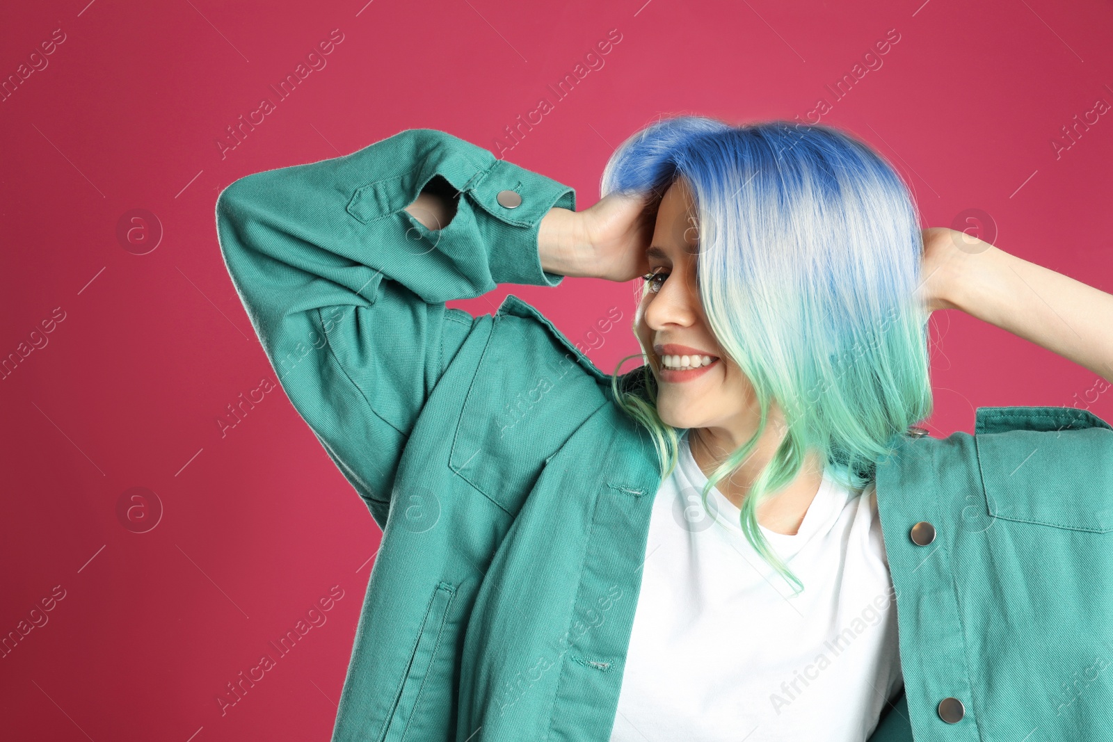 Image of Portrait of young woman with dyed long curly hair on pink background