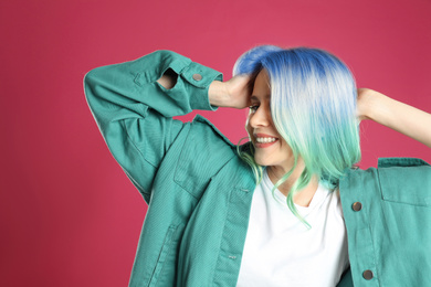 Portrait of young woman with dyed long curly hair on pink background