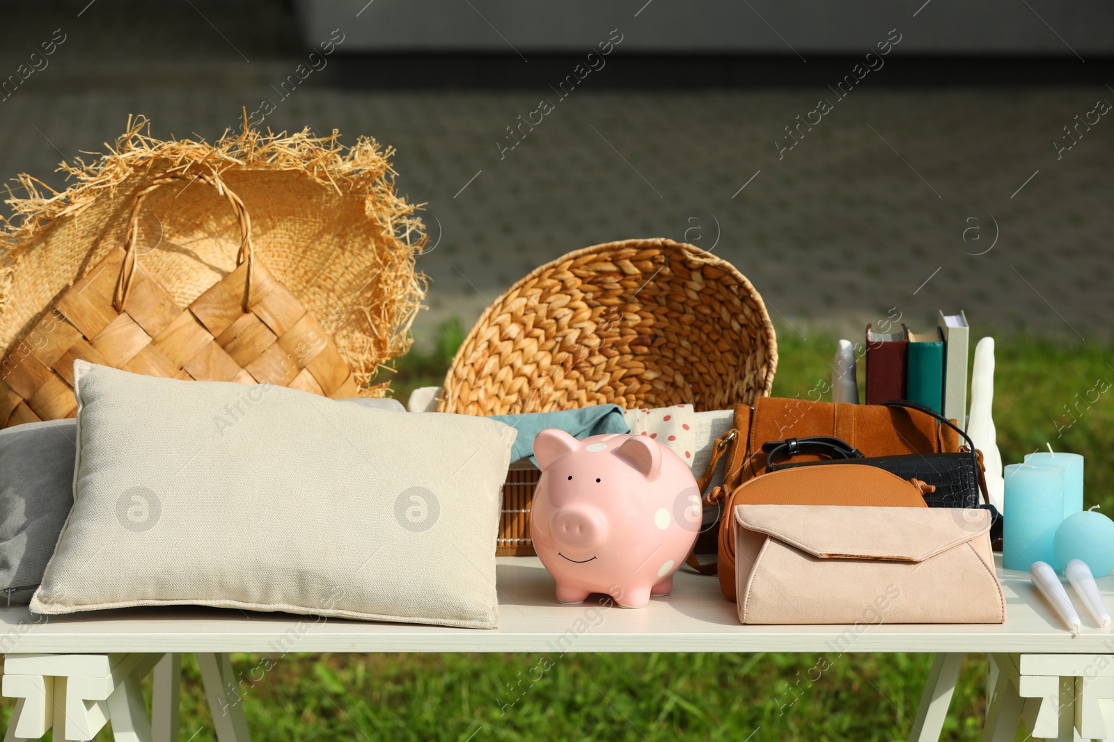 Photo of Many different items on white table outdoors. Garage sale