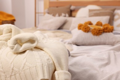 Photo of Warm sweater near bed in room, space for text. Home textile