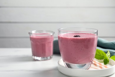 Photo of Glasses of blackberry smoothie with mint on white table, space for text
