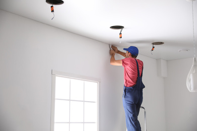 Photo of Worker installing stretch ceiling in empty room. Space for text