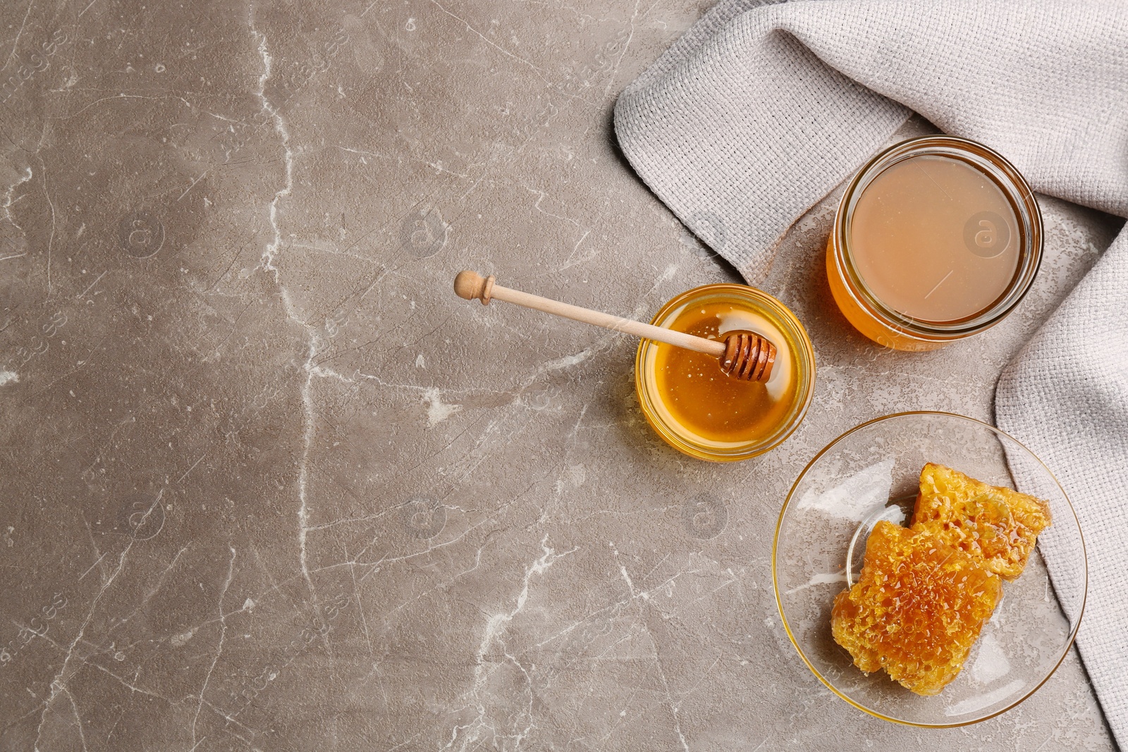 Photo of Tasty honey and combs on brown marble table, flat lay. Space for text