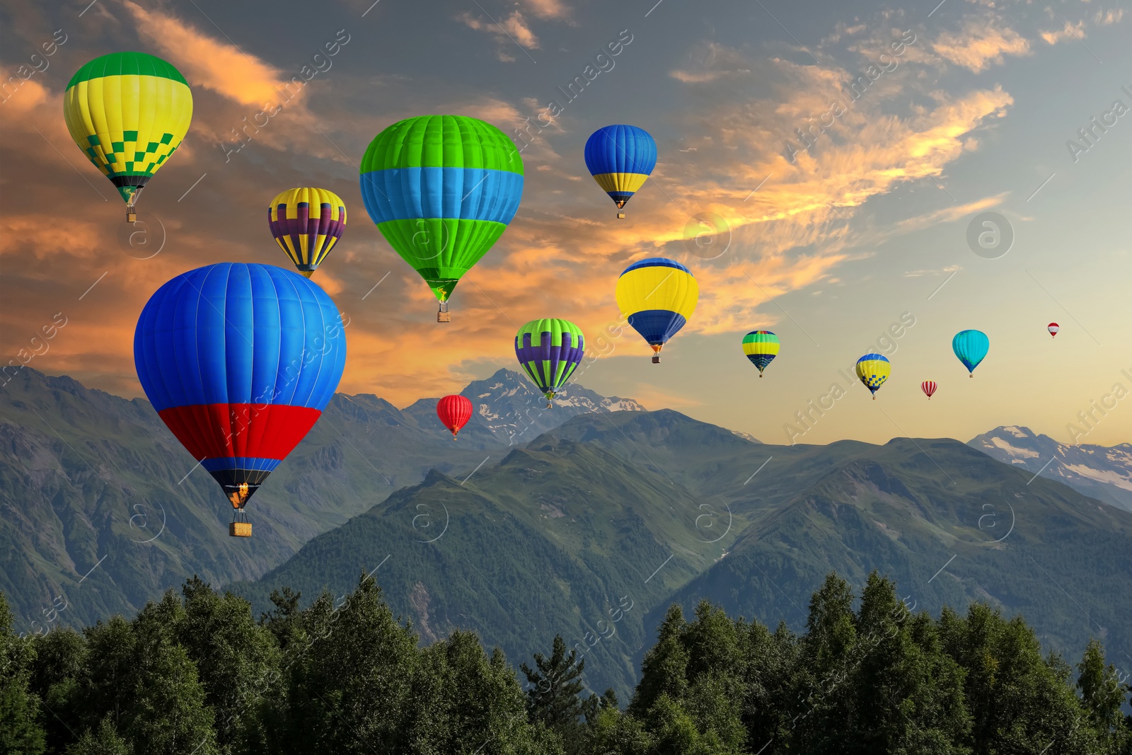 Image of Bright hot air balloons flying in sunset sky over mountains