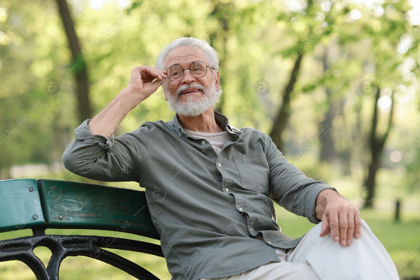 Photo of Portrait of happy grandpa with glasses on bench in park