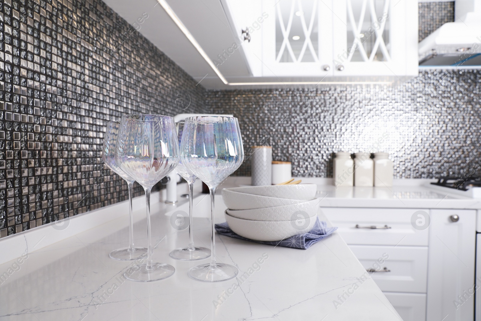 Photo of Beautiful ceramic dishware and glasses on countertop in modern kitchen