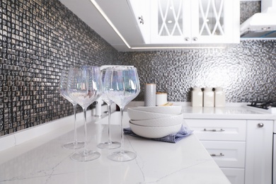 Beautiful ceramic dishware and glasses on countertop in modern kitchen