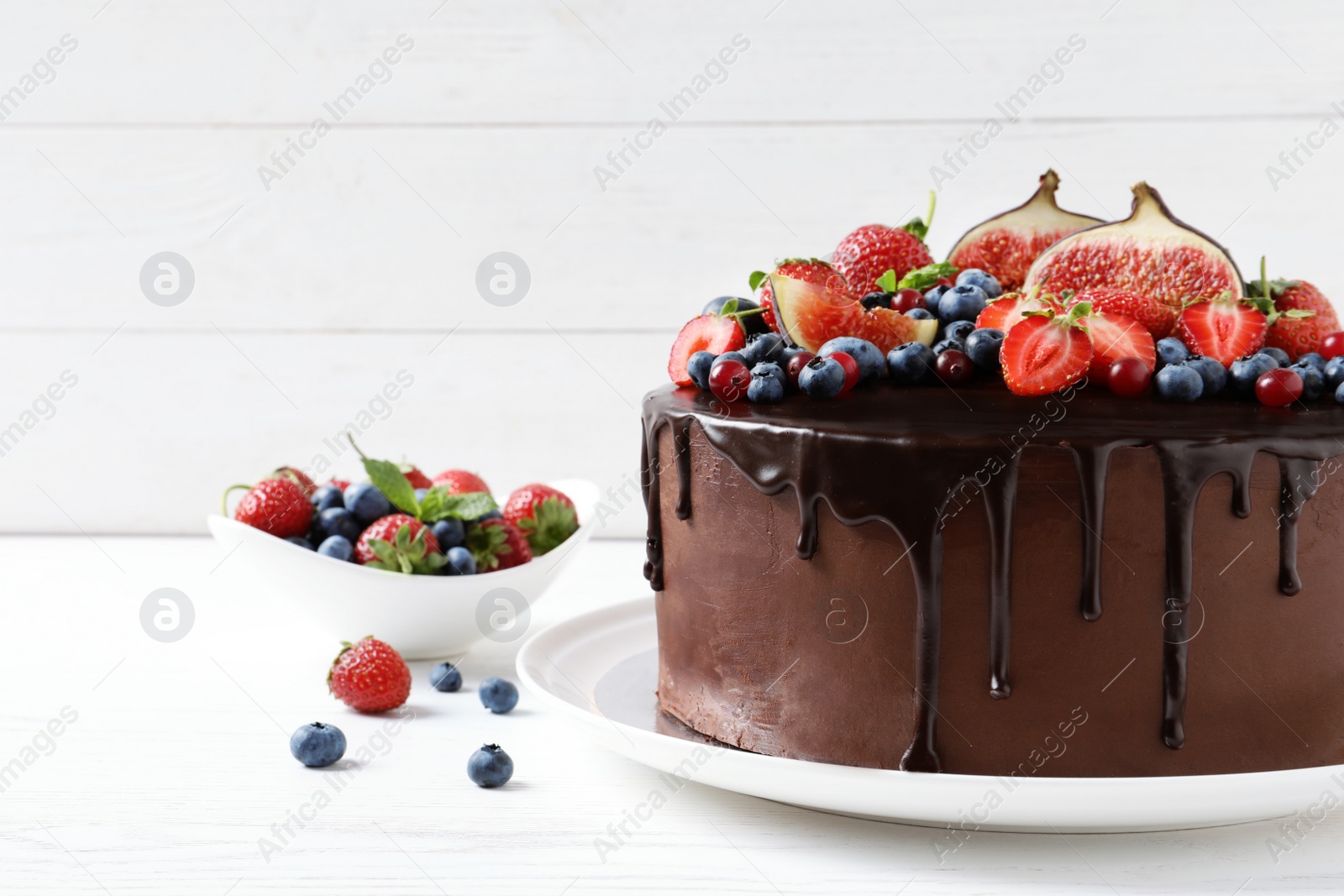 Photo of Fresh delicious homemade chocolate cake with berries on table against wooden background. Space for text