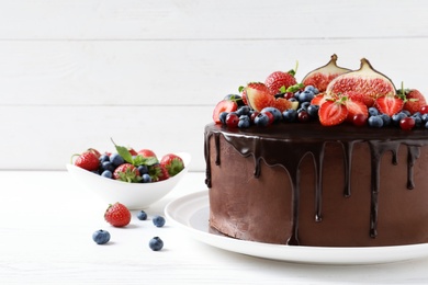 Photo of Fresh delicious homemade chocolate cake with berries on table against wooden background. Space for text