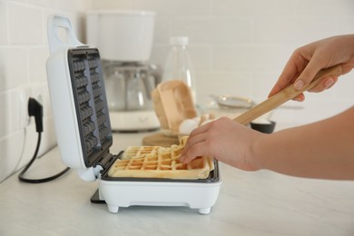 Photo of Woman making delicious Belgian waffles in kitchen, closeup