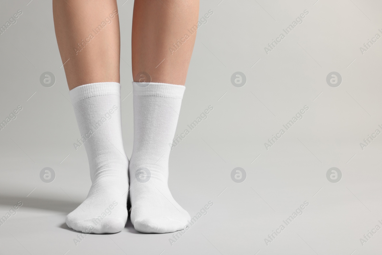 Photo of Woman in stylish white socks on light grey background, closeup. Space for text