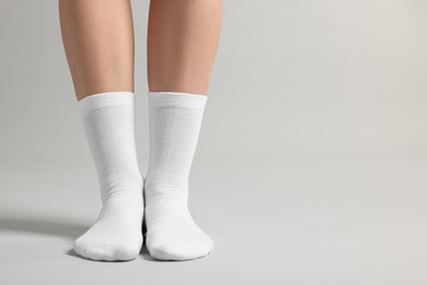 Photo of Woman in stylish white socks on light grey background, closeup. Space for text