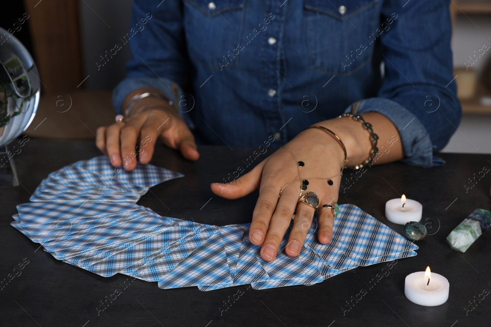 Photo of Fortune teller predicting future on spread of tarot cards at grey table indoors, closeup