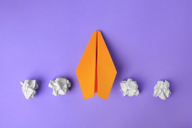 Photo of Idea concept. Handmade plane and crumpled piecespaper on violet background, flat lay
