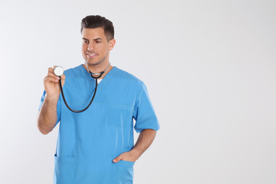 Doctor with stethoscope on light grey background. Space for text