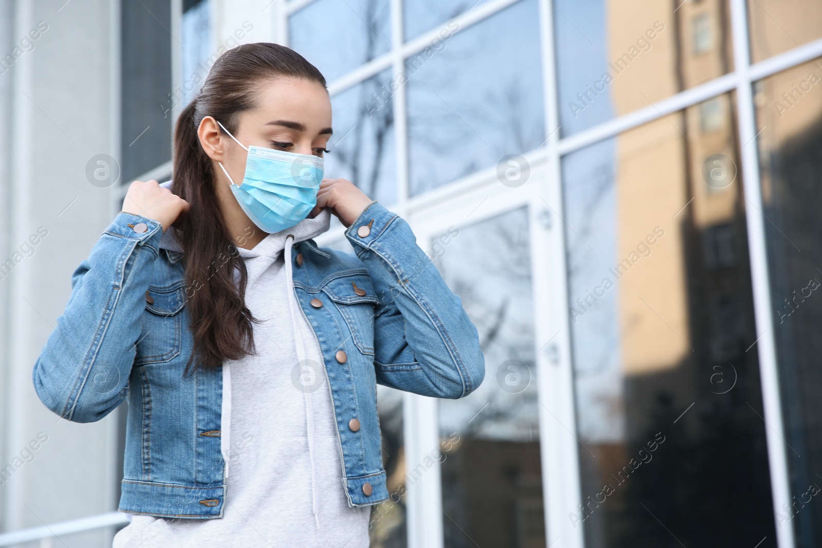 Photo of Woman wearing disposable mask outdoors. Dangerous virus